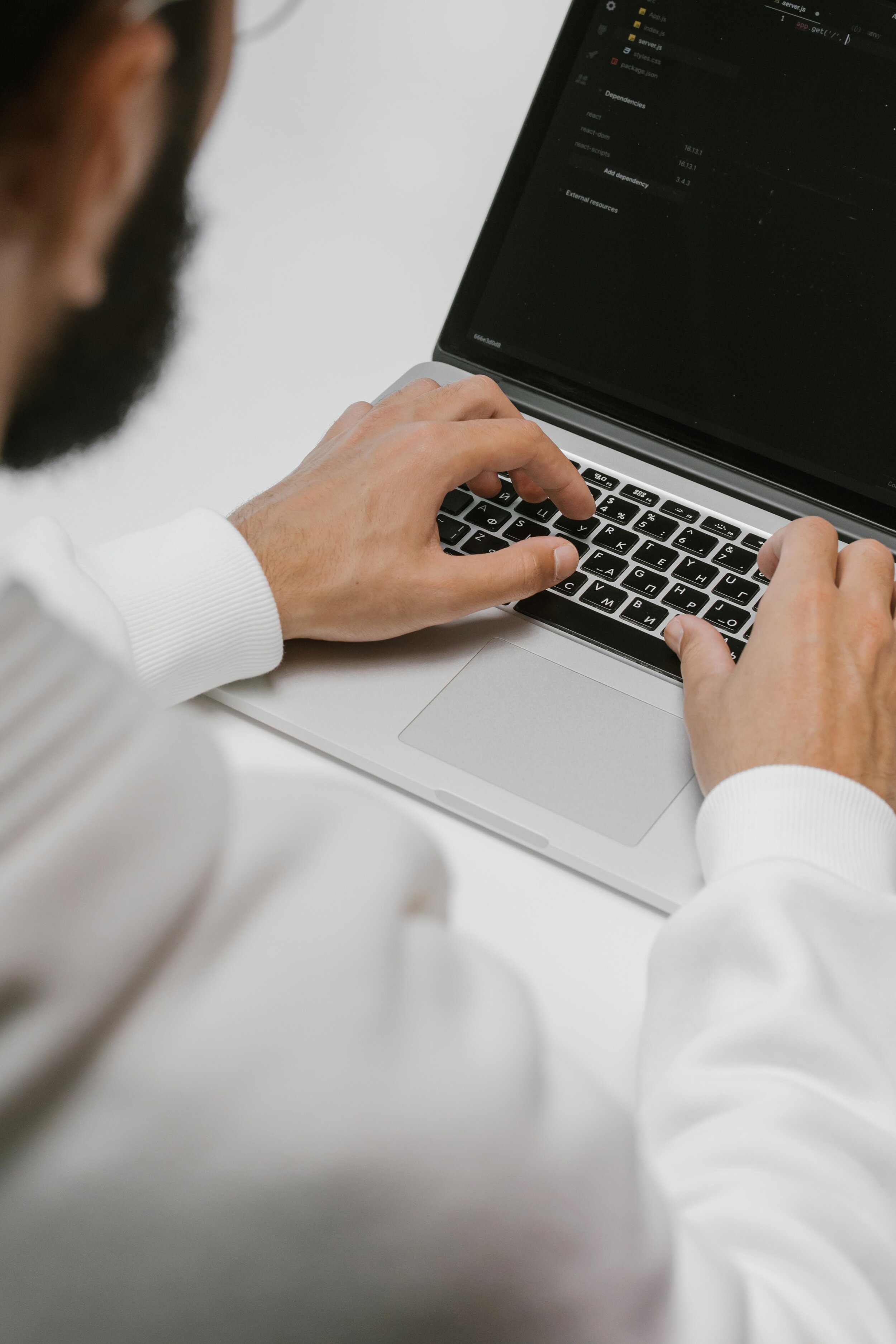 Man wearing white dress shirt using a laptop to make cybersecurity updates
